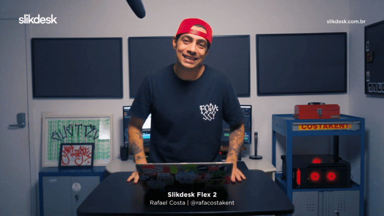 imagem do produtor Rafael Costakent no centro com uma mesa slikdesk flex preta com notebook ele está de camiseta preta basica com bone vermelho virado para trás.