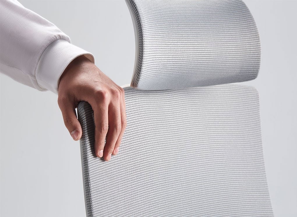 detalhe de uma mão segurando o encosto de tecido mesh da cadeira slikdesk ergos